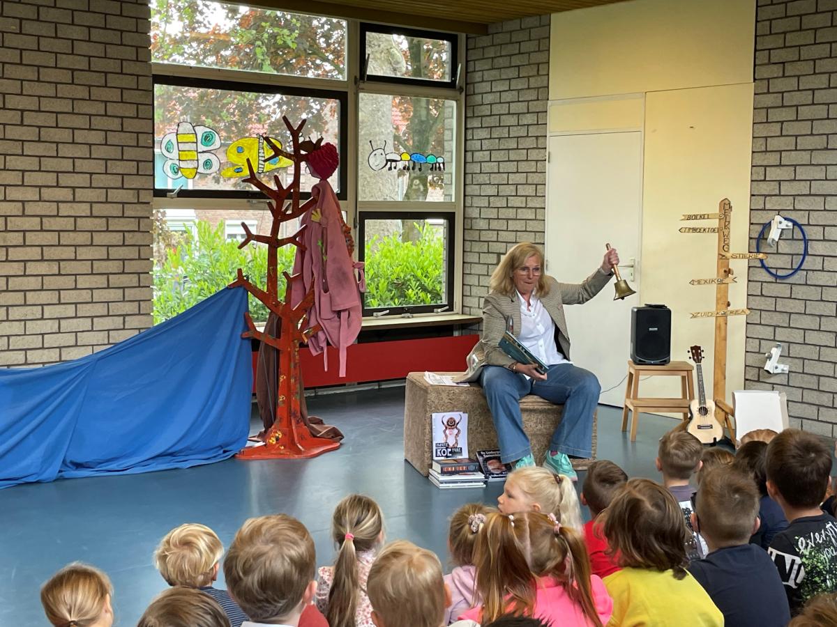 Joes Boonen zit voor een groep kinderen en luidt een koebel