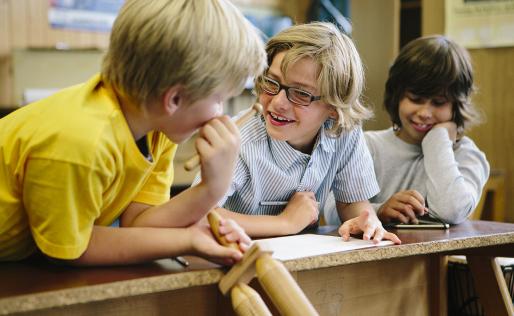 Drie jongens leunen op een tafel en praten met elkaar.