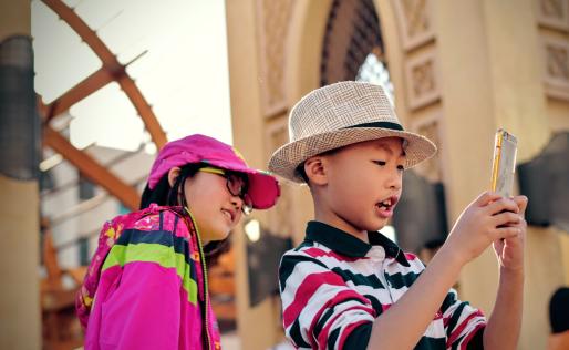 Twee kinderen maken een selfie met een oud gebouw op de achtergrond