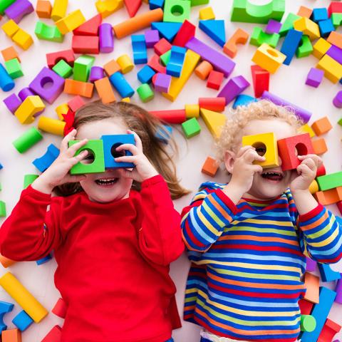 Twee kinderen liggen op de grond en spelen met blokken voor hun ogen.